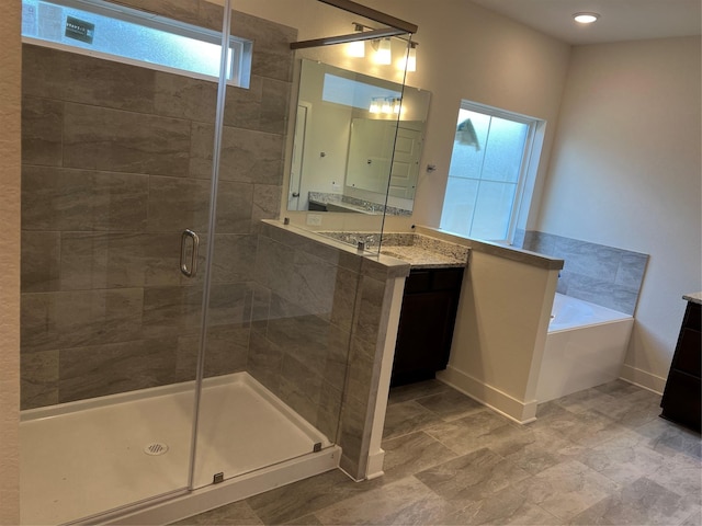 bathroom with baseboards, vanity, a bath, and a shower stall