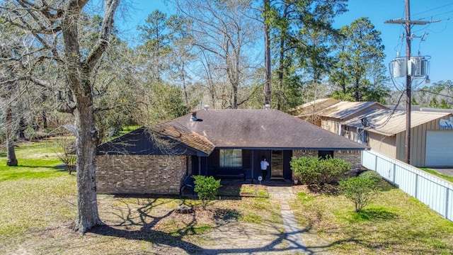 view of front of property featuring brick siding, a shingled roof, a front lawn, and fence