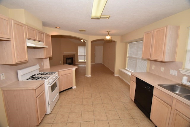 kitchen with light brown cabinets, white gas stove, light countertops, black dishwasher, and under cabinet range hood