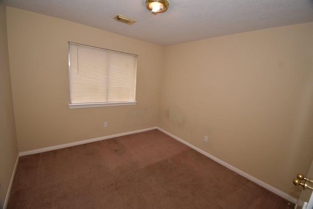 carpeted empty room featuring baseboards, visible vents, and a textured ceiling