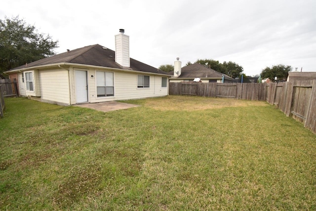 back of property featuring a yard, a fenced backyard, and a chimney