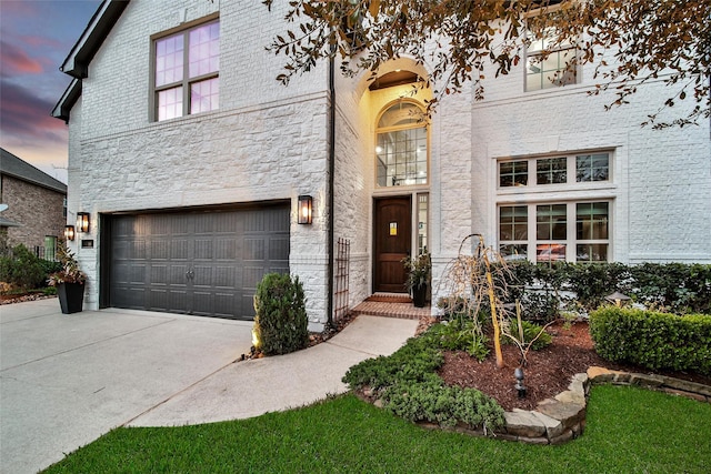 view of front of property with a garage, brick siding, stone siding, and driveway