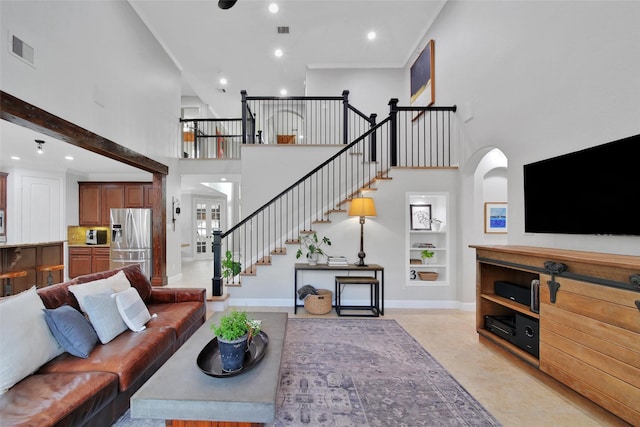 living area featuring visible vents, baseboards, built in features, stairs, and a towering ceiling