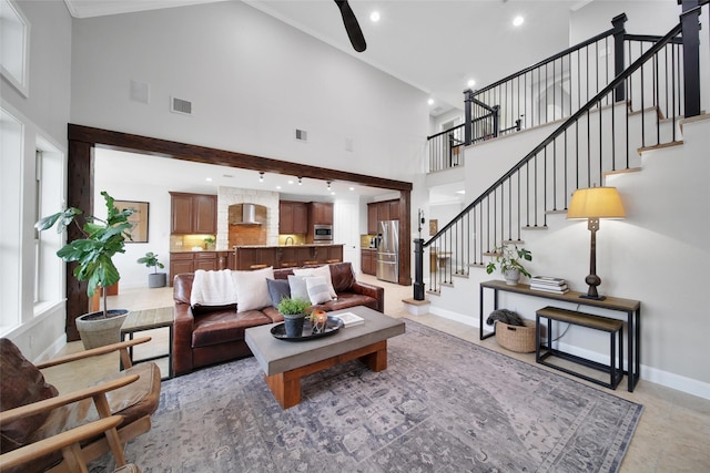 living area featuring stairway, baseboards, visible vents, and a towering ceiling