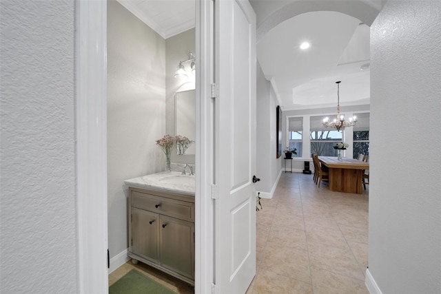 hallway with arched walkways, light tile patterned flooring, baseboards, and a sink