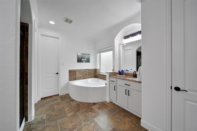 bathroom with stone tile flooring, visible vents, a bath, and vanity