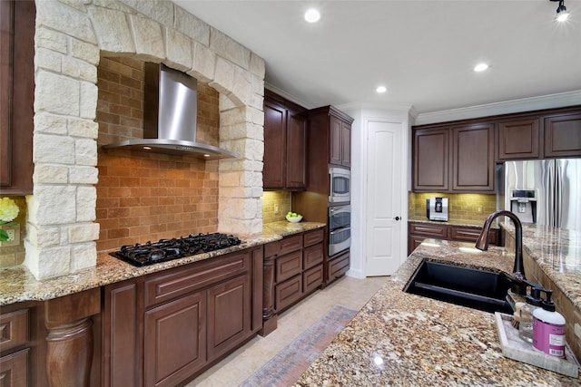 kitchen with a sink, tasteful backsplash, appliances with stainless steel finishes, and wall chimney exhaust hood