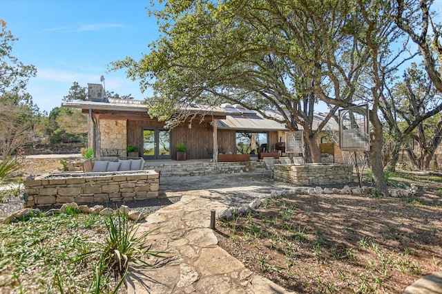 rear view of property with a patio area, stone siding, and french doors