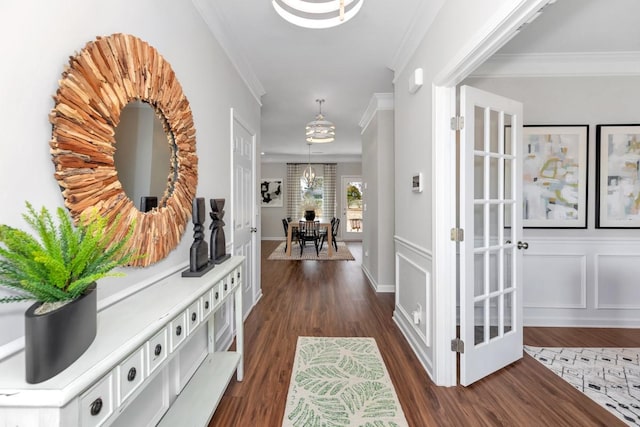 entrance foyer with dark wood-style floors, a decorative wall, and ornamental molding