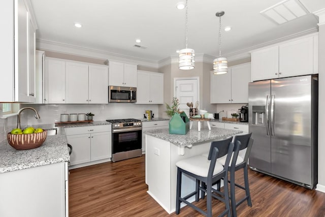 kitchen with ornamental molding, a sink, a kitchen island, stainless steel appliances, and white cabinets