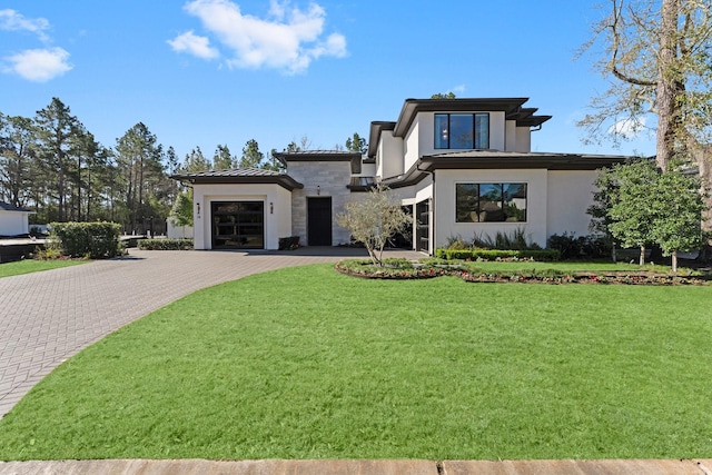 contemporary house with a front yard, metal roof, decorative driveway, an attached garage, and a standing seam roof