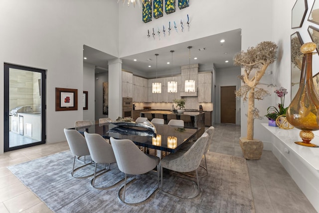 dining space with light tile patterned flooring, recessed lighting, ornate columns, and a towering ceiling