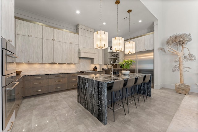 kitchen featuring tasteful backsplash, a center island with sink, dark stone counters, a kitchen breakfast bar, and modern cabinets