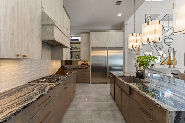 kitchen featuring visible vents, a sink, dark stone countertops, appliances with stainless steel finishes, and decorative backsplash