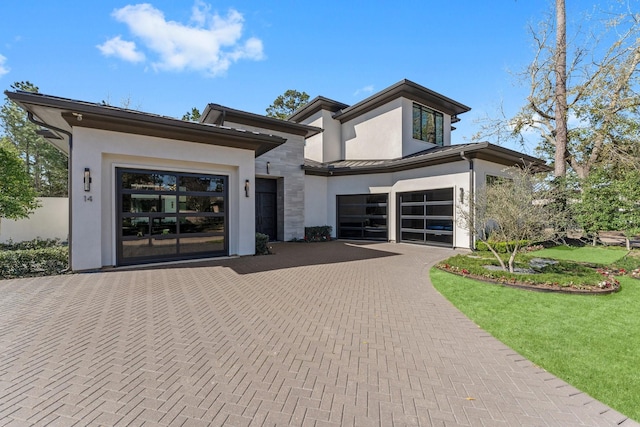 view of front of property featuring stone siding, stucco siding, decorative driveway, and a garage