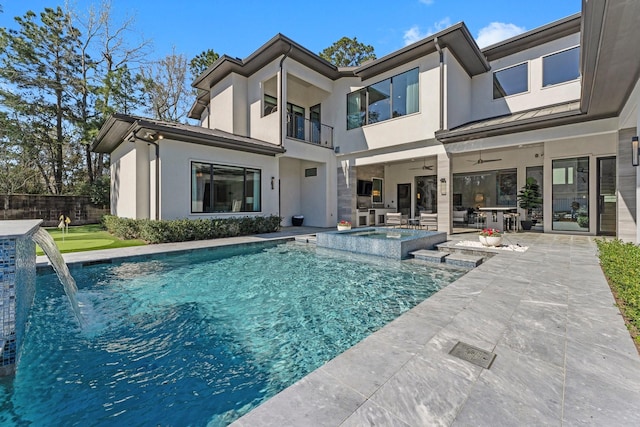 rear view of property with a patio, a balcony, a ceiling fan, a pool with connected hot tub, and stucco siding