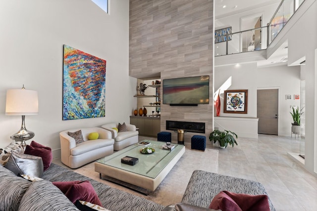 living area featuring a towering ceiling, tile patterned flooring, and a tile fireplace