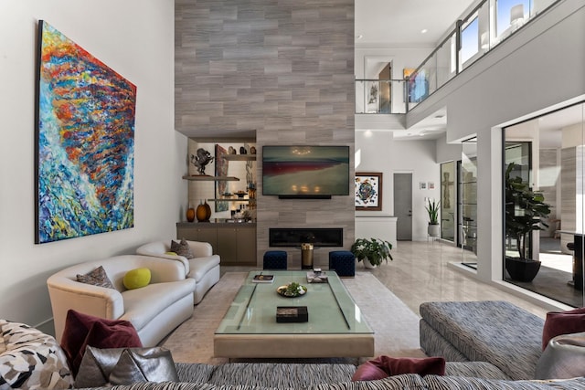 living area with a towering ceiling and a tile fireplace