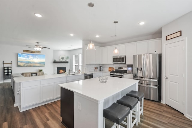 kitchen with a kitchen island, a peninsula, a sink, stainless steel appliances, and open floor plan