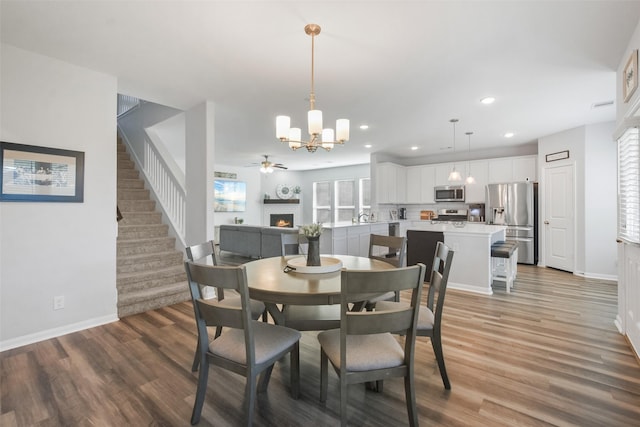 dining area featuring a brick fireplace, stairway, recessed lighting, and light wood-style floors