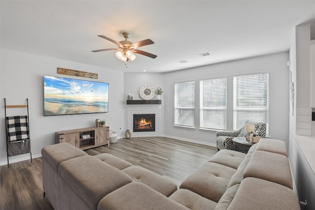 living room with visible vents, baseboards, wood finished floors, and a fireplace