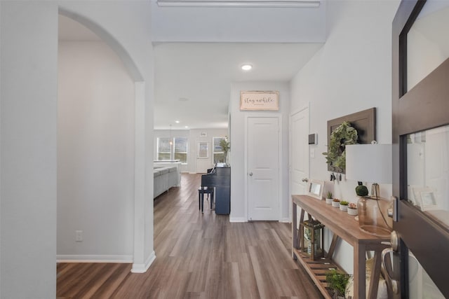 foyer featuring recessed lighting, wood finished floors, arched walkways, and baseboards