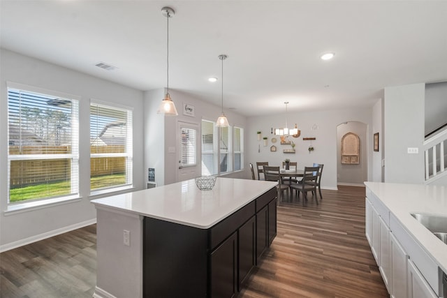 kitchen featuring recessed lighting, arched walkways, light countertops, baseboards, and dark wood-style flooring