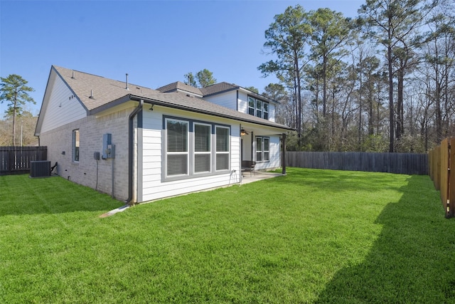 back of property with brick siding, a lawn, and a fenced backyard