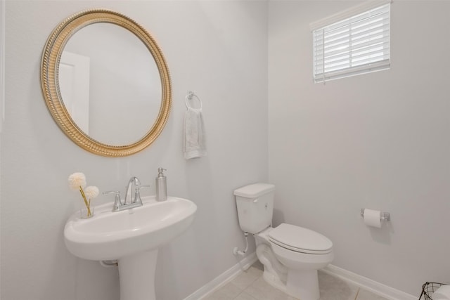 bathroom featuring tile patterned floors, toilet, baseboards, and a sink