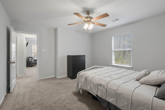 carpeted bedroom featuring visible vents, multiple windows, a ceiling fan, and baseboards