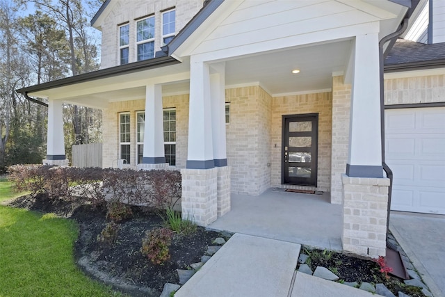 doorway to property featuring a garage, brick siding, and a porch