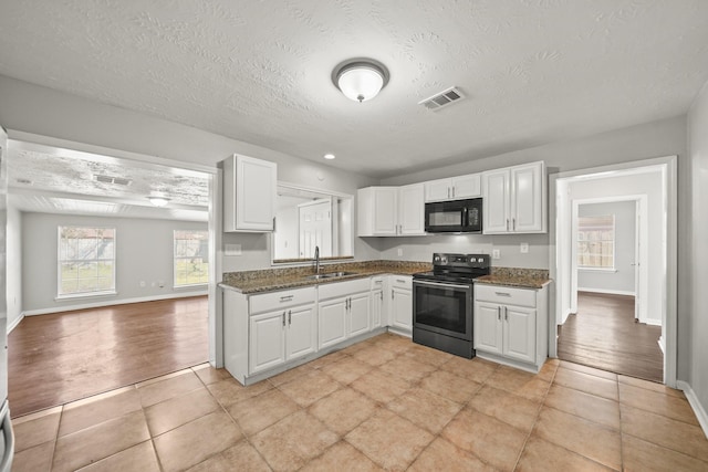 kitchen with visible vents, a sink, white cabinetry, stainless steel electric range, and black microwave