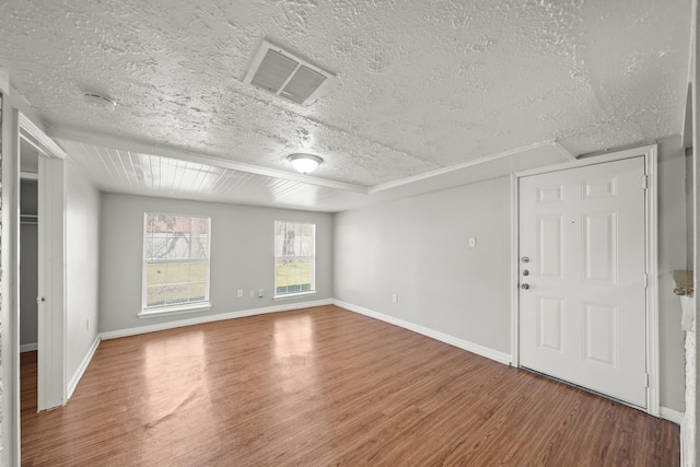 empty room featuring visible vents, baseboards, a textured ceiling, and wood finished floors