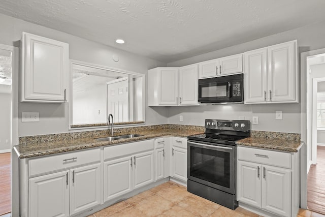 kitchen featuring dark stone counters, stainless steel electric range, a sink, white cabinets, and black microwave