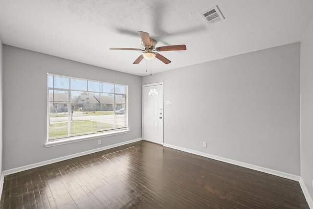 spare room with visible vents, ceiling fan, baseboards, and dark wood-style flooring