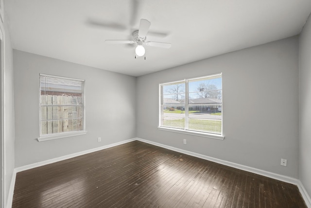 unfurnished room with baseboards, dark wood finished floors, and a ceiling fan