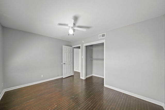 unfurnished bedroom with baseboards, visible vents, dark wood finished floors, ceiling fan, and a closet