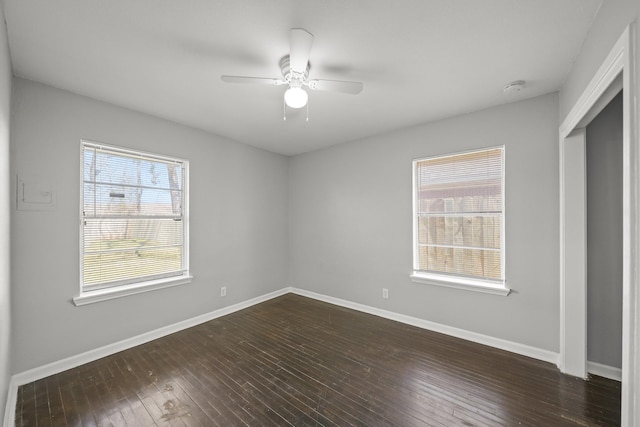 unfurnished bedroom featuring baseboards, multiple windows, dark wood finished floors, and a ceiling fan