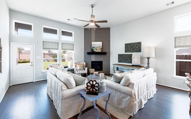 living area with visible vents, baseboards, dark wood-style floors, and a fireplace