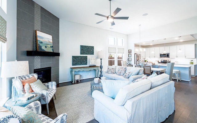 living room featuring dark wood-type flooring, a fireplace, and ceiling fan