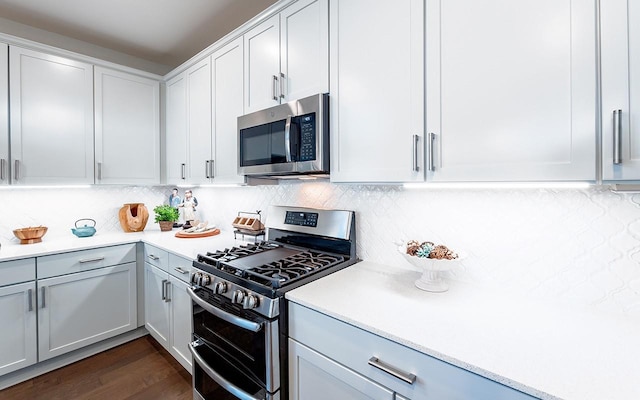 kitchen featuring dark wood-style floors, light countertops, white cabinets, appliances with stainless steel finishes, and backsplash