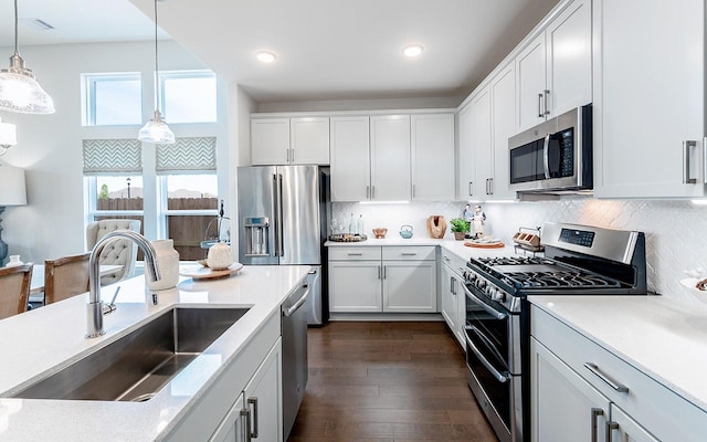 2409 Seaglass Terrace Dr, Katy, TX 77493 - kitchen with stainless steel appliances, a sink, decorative light fixtures, backsplash, and dark wood-style flooring
