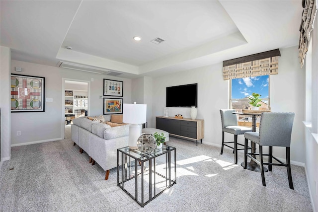 living room with visible vents, a raised ceiling, and baseboards