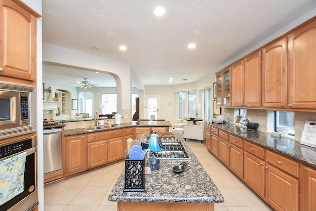 kitchen with light tile patterned floors, dark stone countertops, appliances with stainless steel finishes, and a sink