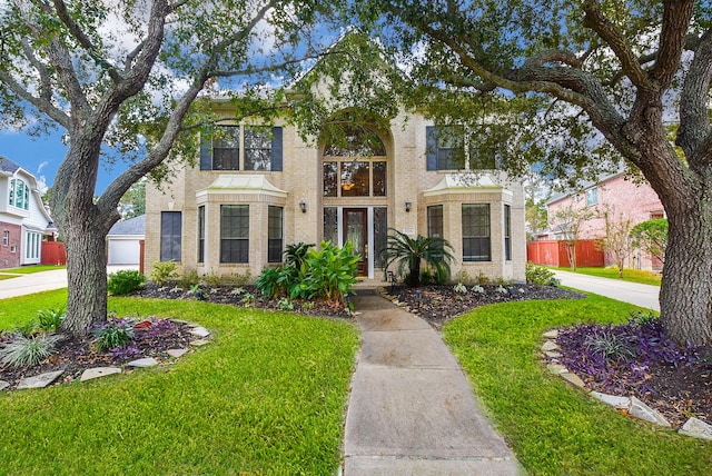 traditional-style home with a front lawn, fence, and brick siding