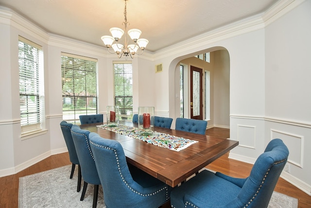 dining space with visible vents, wood finished floors, arched walkways, crown molding, and a chandelier