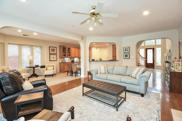 living room featuring recessed lighting, arched walkways, light wood-style flooring, and a ceiling fan