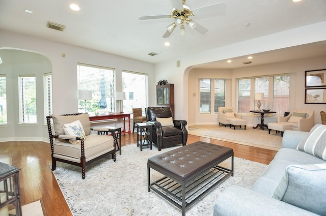 living room with recessed lighting, visible vents, arched walkways, and wood finished floors