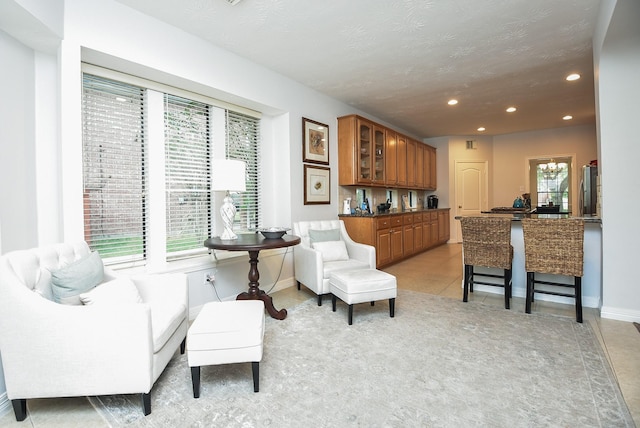 sitting room featuring light tile patterned floors, recessed lighting, a textured ceiling, and baseboards