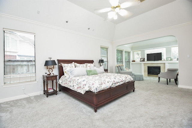 carpeted bedroom with a high end fireplace, crown molding, ceiling fan, baseboards, and arched walkways